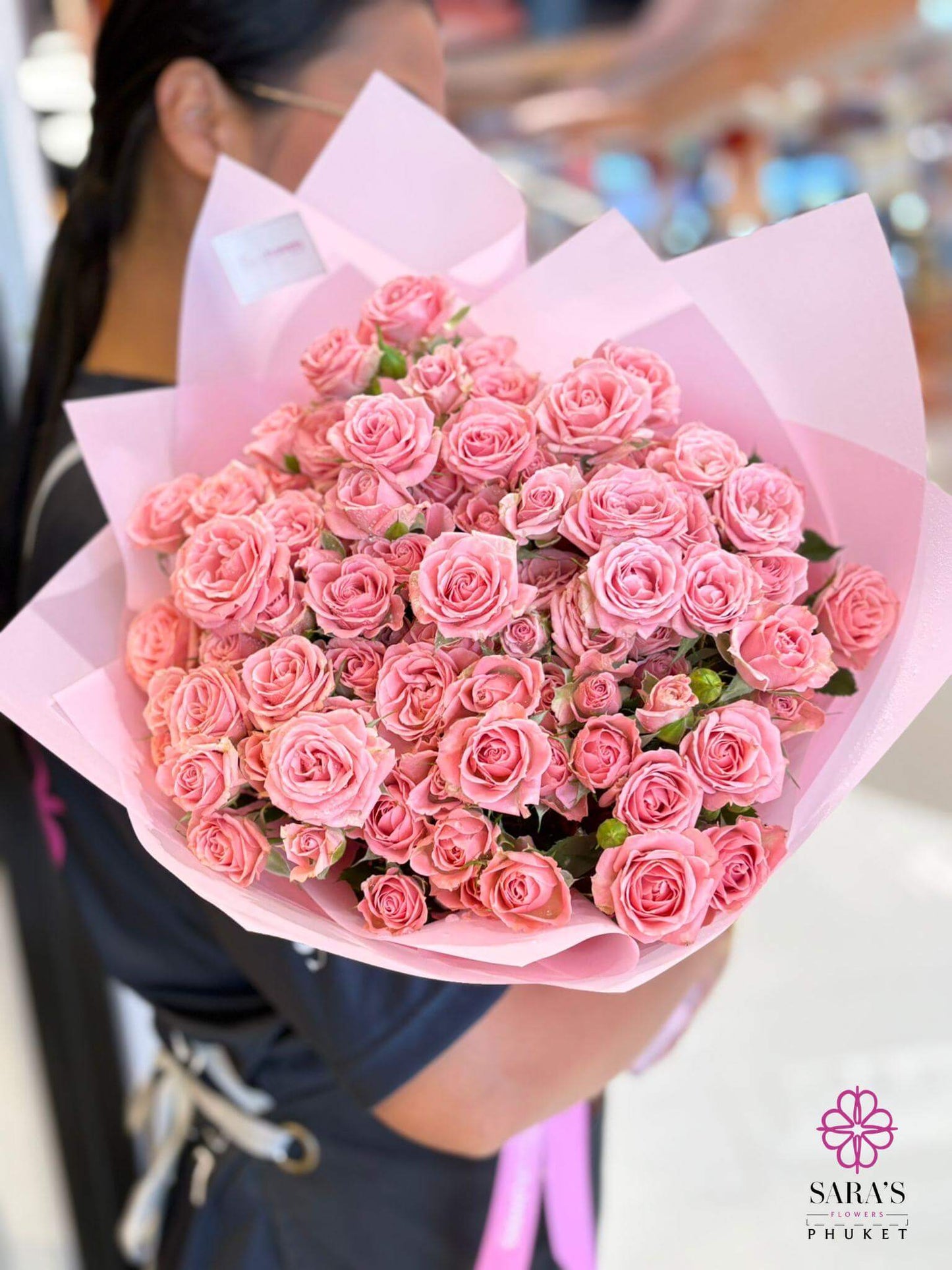 Bouquet of pink roses held by a person, with a blurred background