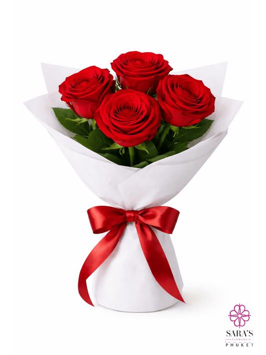 Four long-stem red roses in a luxury white paper wrap with a red satin ribbon by Sara's Flowers Phuket.