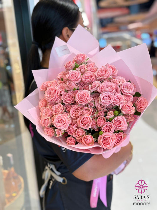 Person holding a large bouquet of pink flowers with a blurred background