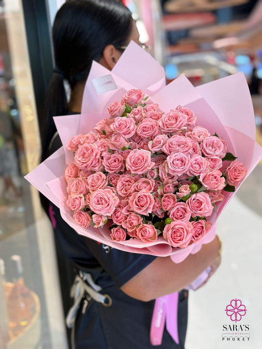 Person holding a large bouquet of pink flowers with a blurred background