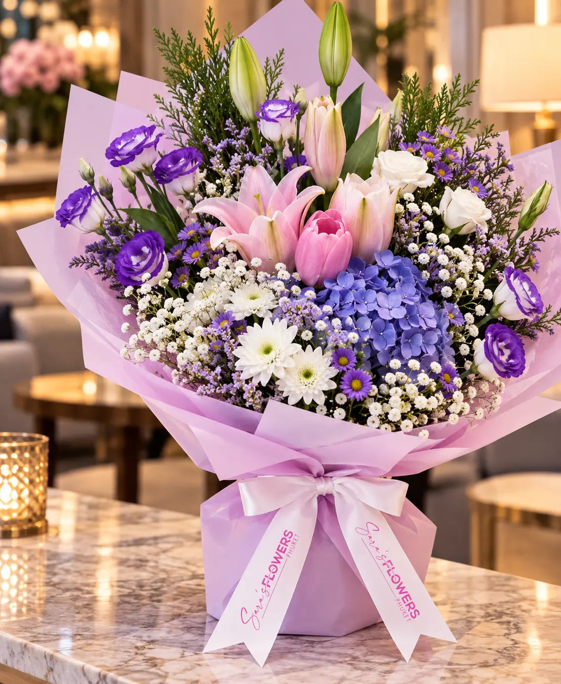 A vibrant floral bouquet wrapped in light purple paper and tied with a white ribbon printed with 'Super Flowers', displayed on a marble countertop in a warmly lit indoor setting.