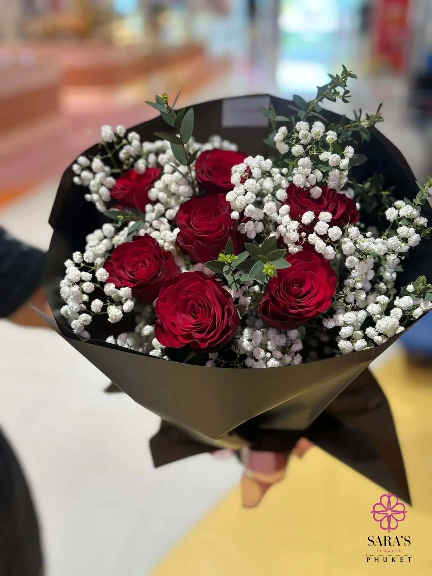 Luxury bouquet with seven red roses, baby’s breath, eucalyptus, and elegant black wrapping by Sara’s Flowers Phuket