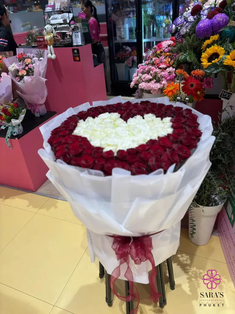 Heart-shaped bouquet of red and white roses in a store setting