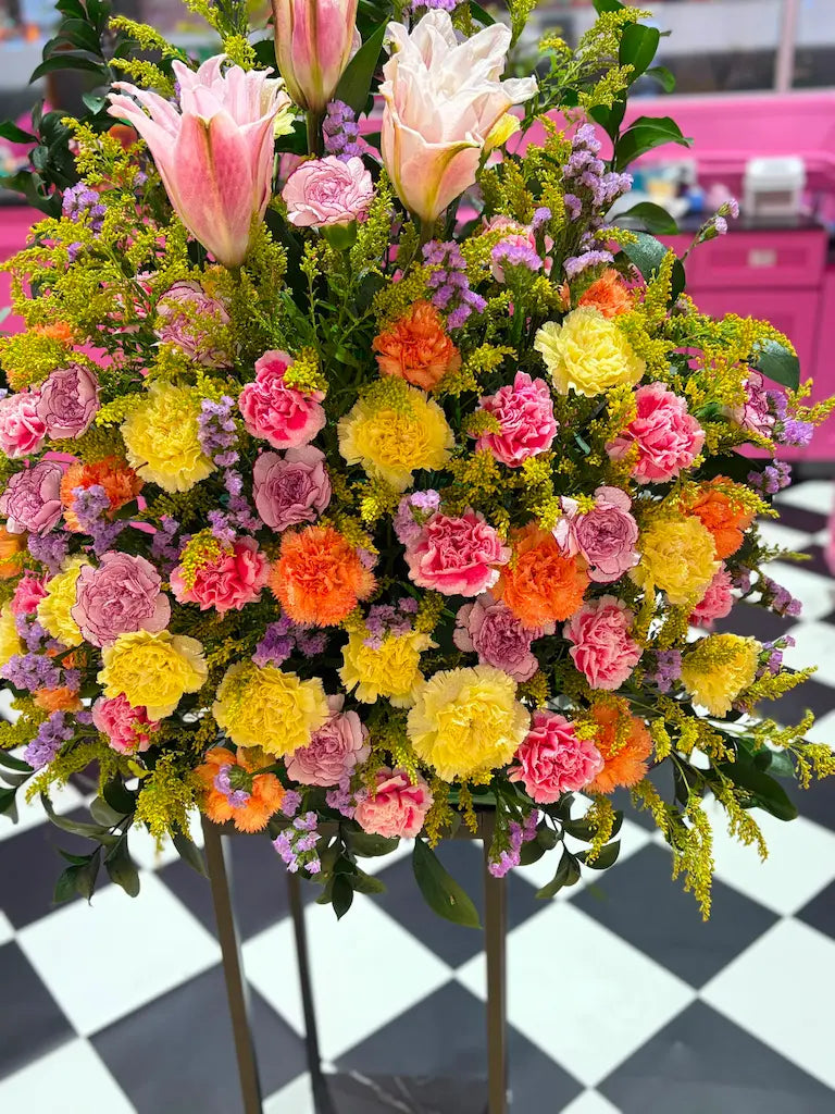 Detailed view of Sunrise Serenade arrangement featuring lilies, carnations, statice and lush greenery