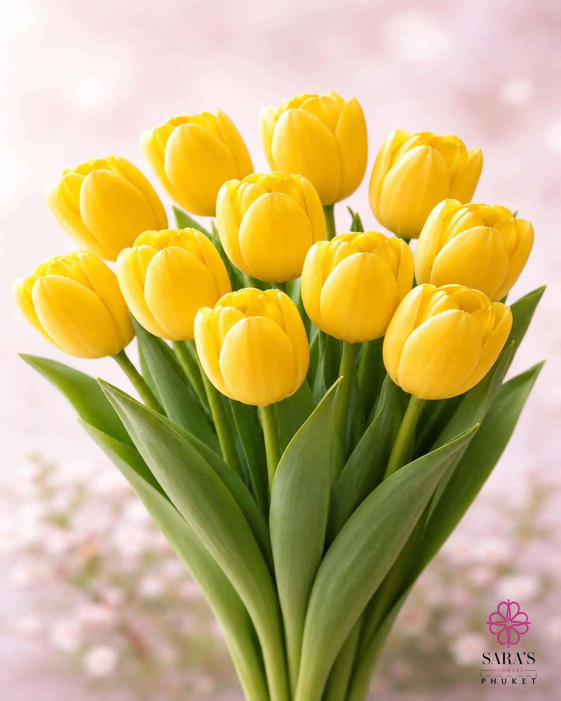 Vibrant yellow tulip bouquet with green stems, elegantly arranged against a soft pink background.