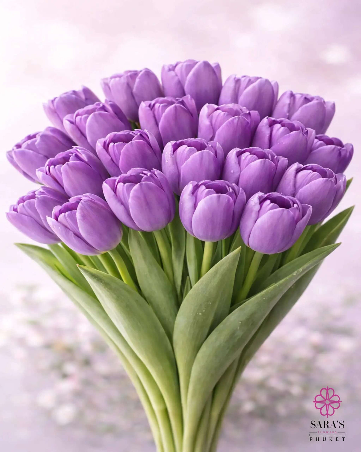Vibrant purple tulip bouquet with fresh green stems, elegantly arranged.