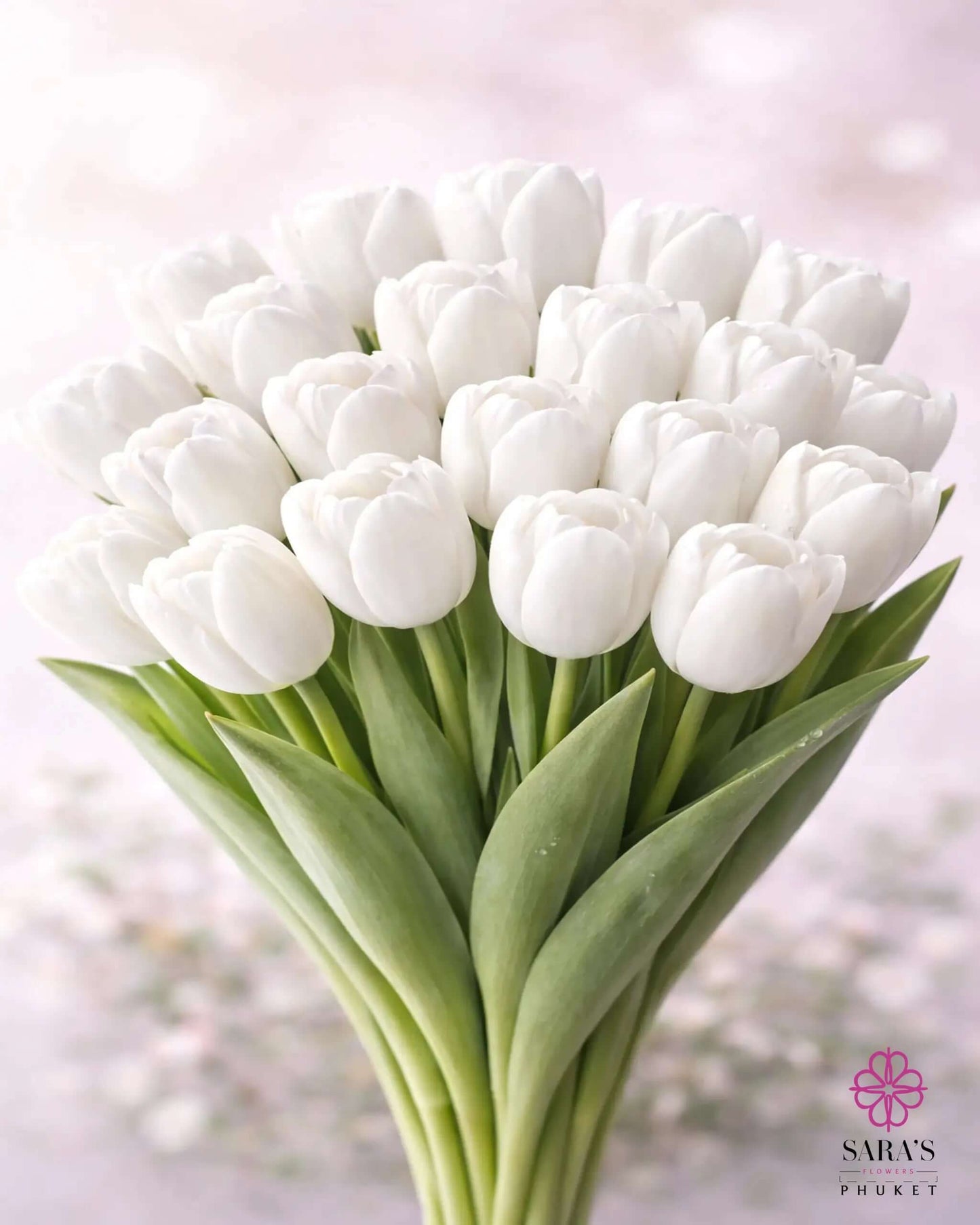 Elegant Sara's Signature Tulip Bouquet with numerous fresh white tulips and green leaves, wrapped in luxury white paper.