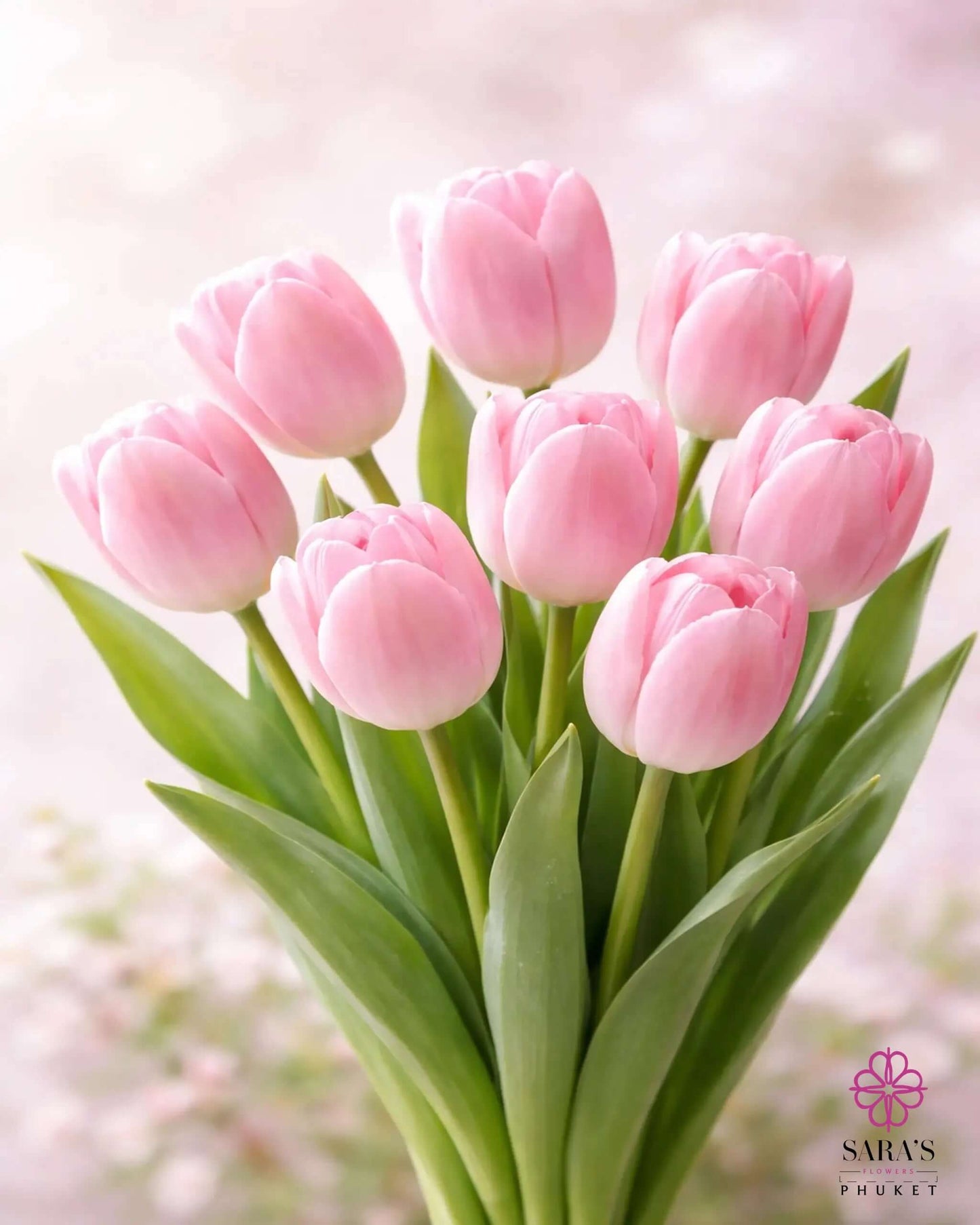 Elegant bouquet of nine fresh pink tulips with green stems, wrapped in luxury white paper.