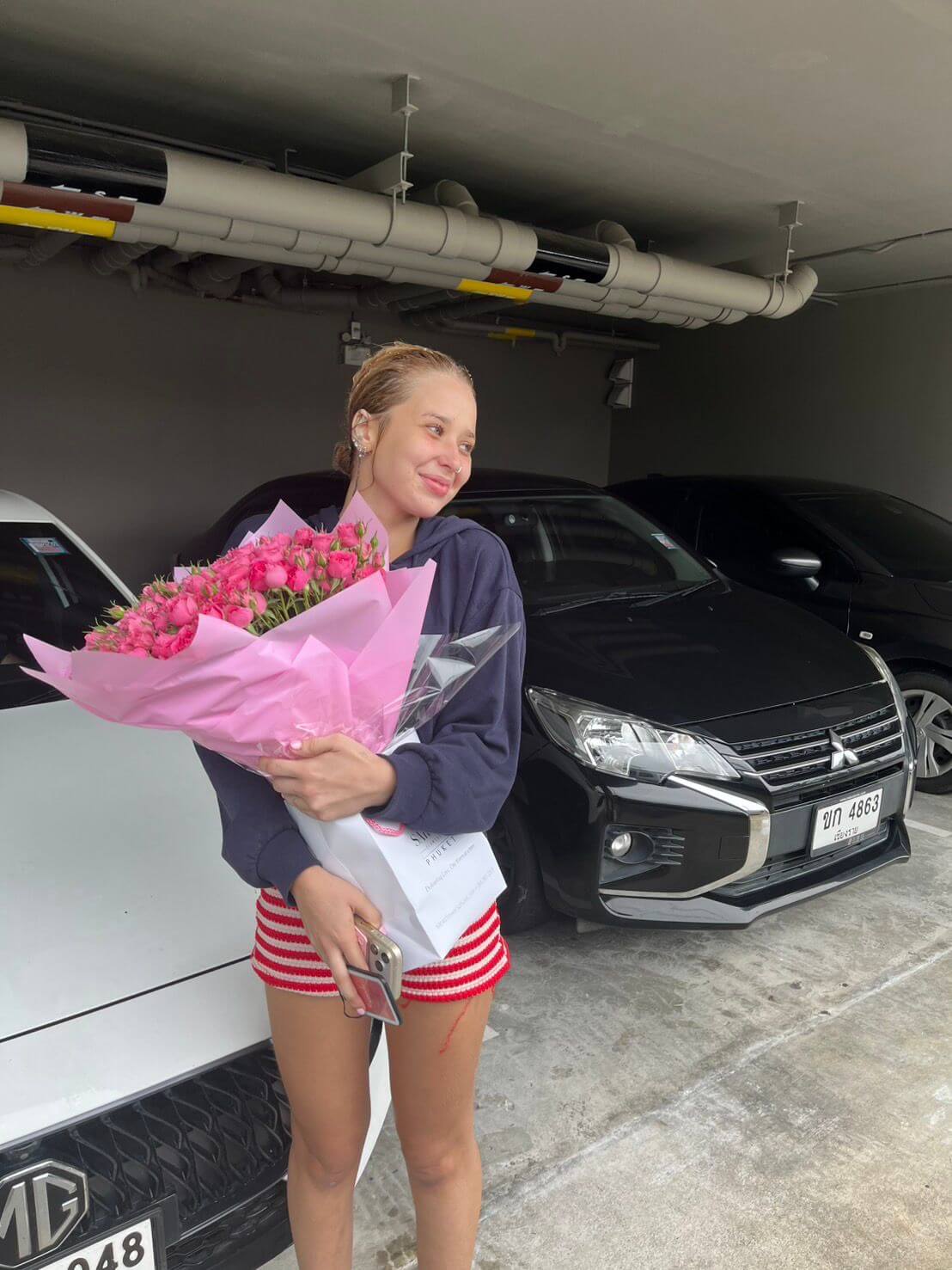 Woman holding flowers in a garage with cars in the background