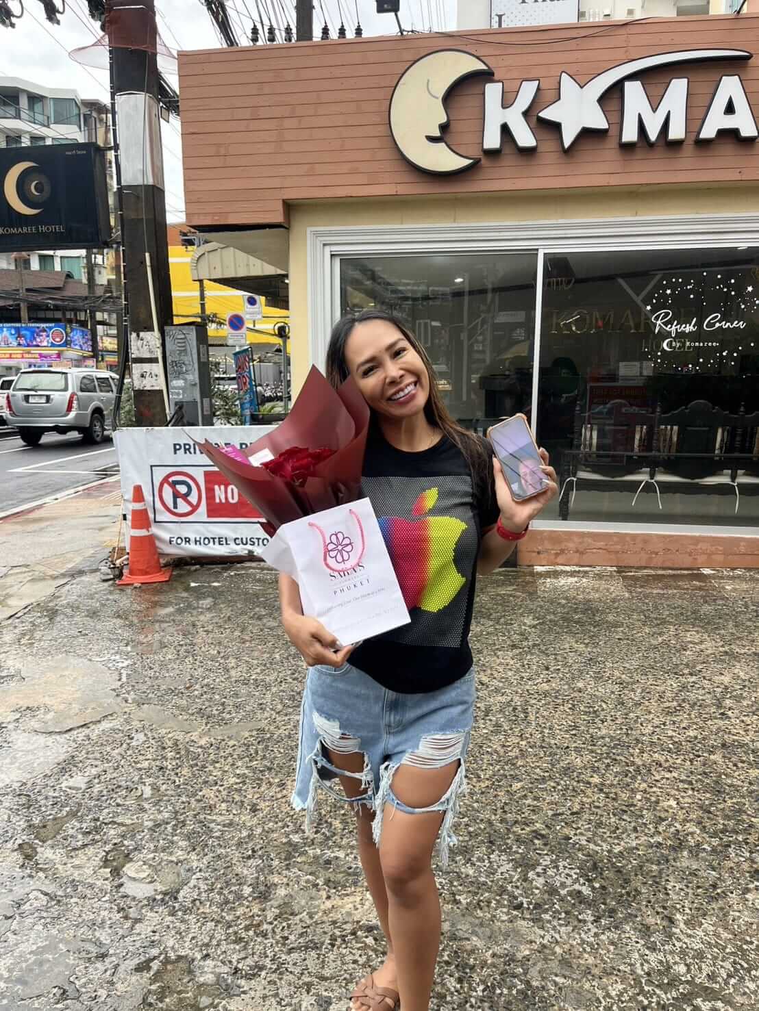 Woman holding a bouquet of flowers and a phone in front of a store