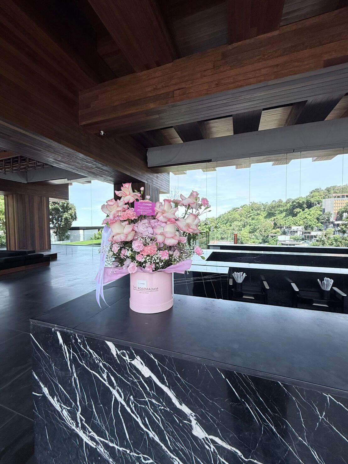 Floral arrangement in a pink box on a black marble counter at a Phuket Hotel with a modern interior background