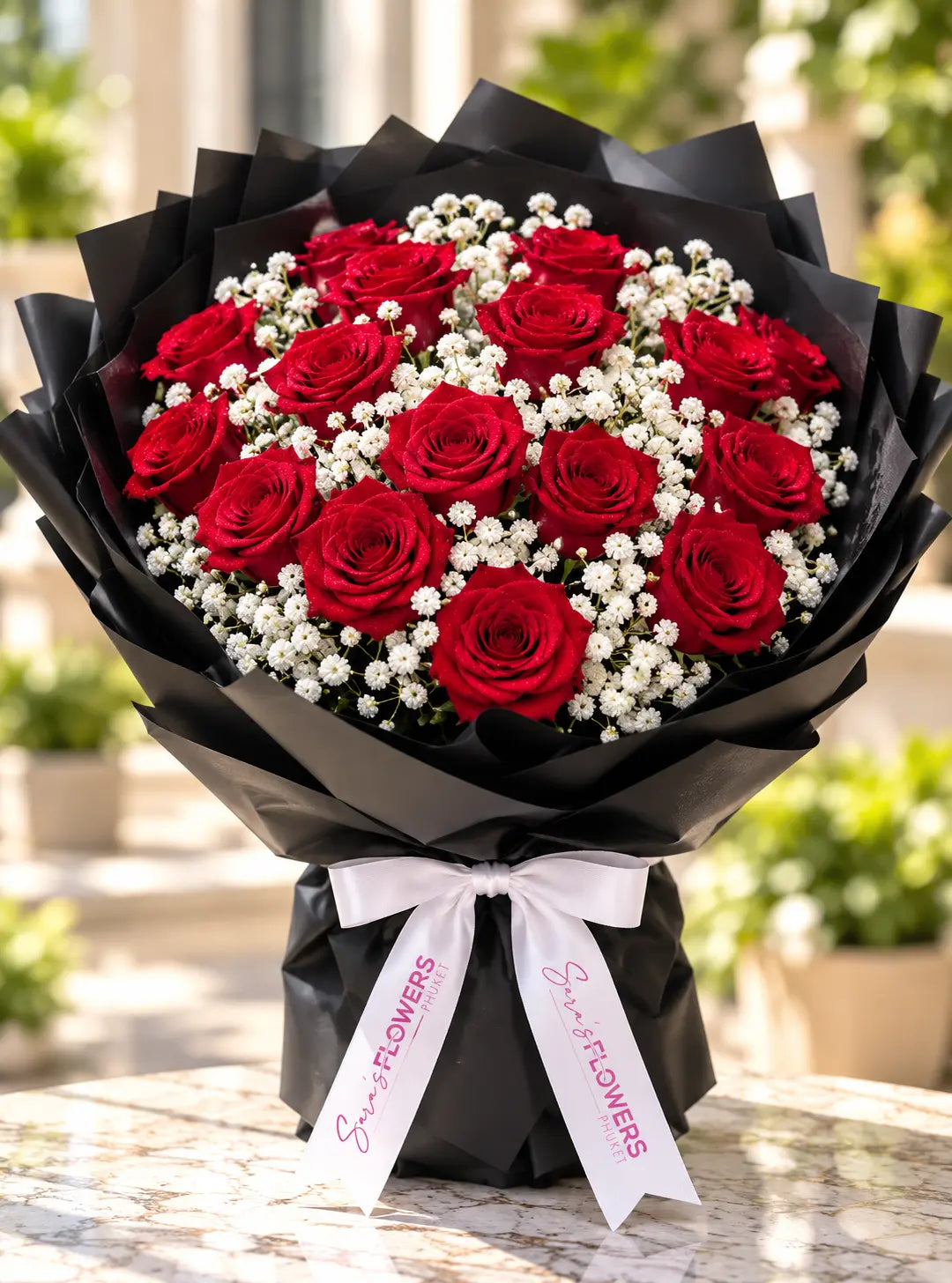 A bouquet of 21 red roses mixed with white baby's breath, wrapped in black paper with a white ribbon printed with 'Super Flowers'.