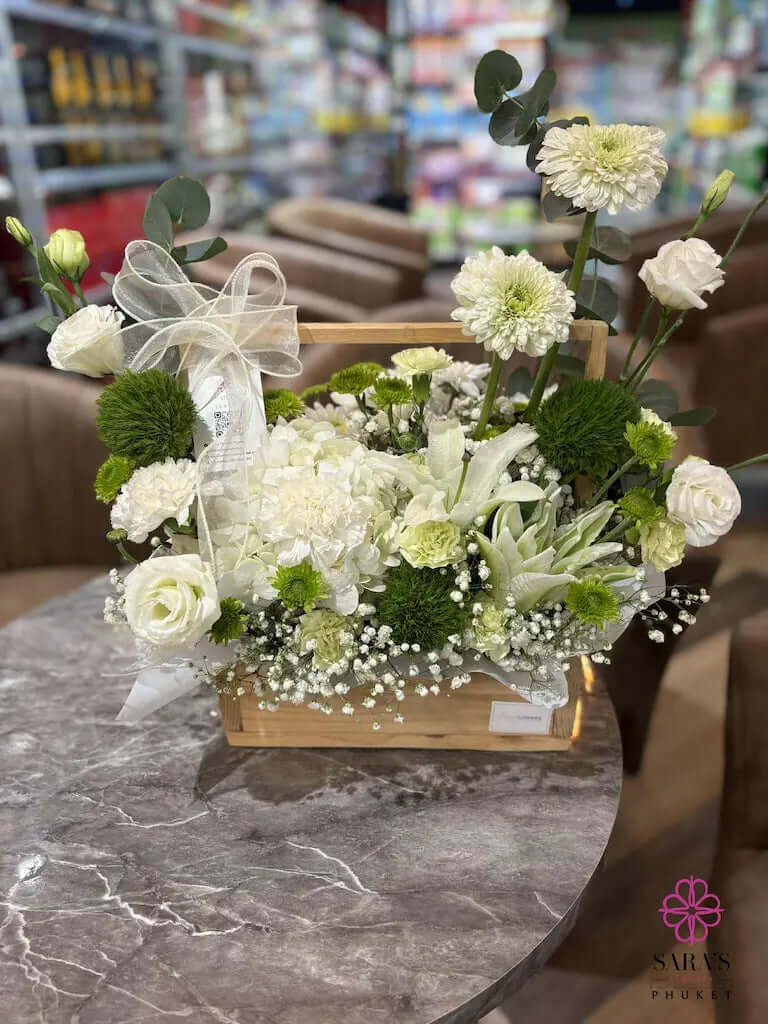 Floral arrangement in a wooden crate on a marble surface with a blurred store background